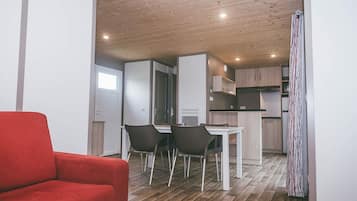 Een compacte leefruimte met een eethoek, kitchenette en een rode bank.