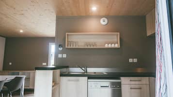 A modern kitchen with a wooden ceiling, a built-in dishwasher, and a shelf above the sink.