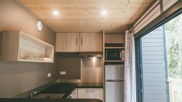 A compact kitchen with wooden cabinets, a microwave, and a small refrigerator.