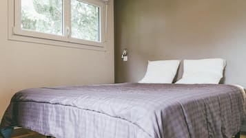 Une chambre à coucher avec un lit, une fenêtre et un luminaire fixé au mur.