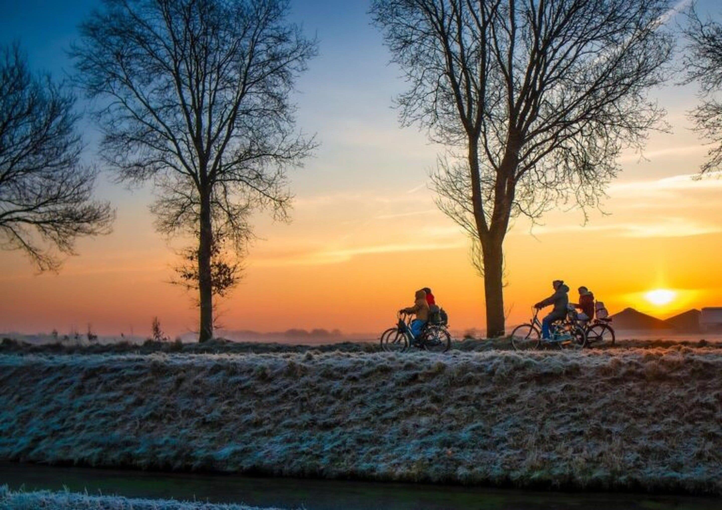 A sunset with cyclists on a frosty path.