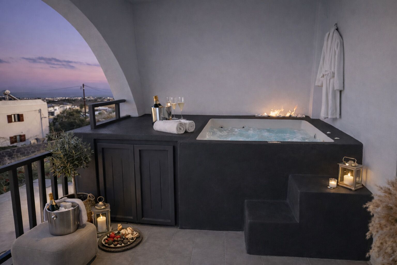 Eine Dachterrasse mit Whirlpool, einem kleinen Esstisch mit Speisen, einer Champagnerflasche und einer Kerze.