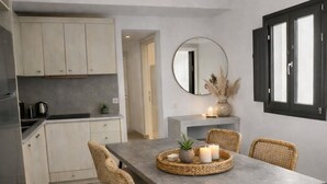 Une cuisine moderne avec un coin repas, comprenant une grande table, des chaises en osier, un luminaire suspendu et un miroir.