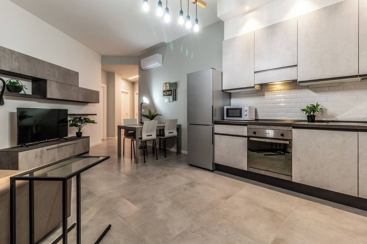 A modern kitchen with a built-in oven, microwave, and a dining area with a table and chairs.