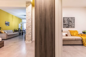 A modern living room with a sofa, a dining area, and a kitchen in the background.
