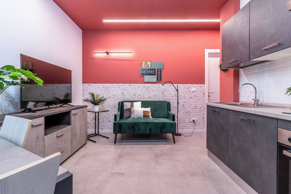 A compact kitchen with a green sofa, a small side table, and a brick-patterned backsplash.