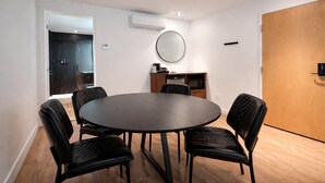 A conference room with a round table, black chairs, a wooden door, and an air conditioning unit. - Suite with 2 Queen Beds | Downtown Quebec City (Québec City)