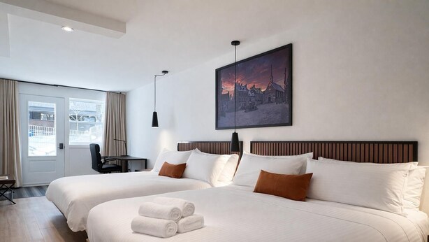 A hotel room with two beds, a desk, a chair, a painting, and a view of the outside. - Suite with 2 Queen Beds | Downtown Quebec City (Québec City)