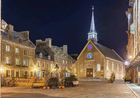 Un bâtiment historique doté d’un clocher et d’une horloge imposants, entouré de rues pavées et bordé d’édifices à l’architecture traditionnelle.