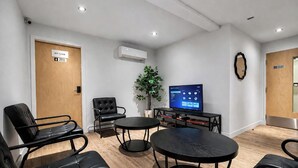 A room with a flat-screen TV, a potted plant, and a seating area with chairs and tables. - Room with 2 Queen Beds | Downtown Quebec City (Québec City)