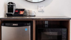 A compact kitchenette with a dishwasher, a coffee machine, a microwave, and a round mirror on the wall. - Room with 2 Queen Beds | Downtown Quebec City (Québec City)