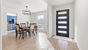 Uma área de refeições com mesa e cadeiras, um lustre e vista para a cozinha.