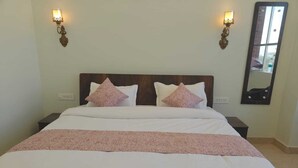 A neatly made bed with white and pink linens, two bedside lamps, and a large mirror on the wall. - Hotel funday (Jaipur)