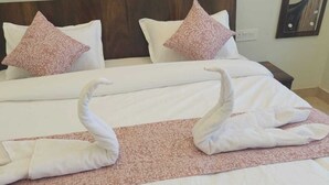 A hotel room with a large bed, two pillows, a wooden headboard, and a mirror on the wall. - Hotel funday (Jaipur)