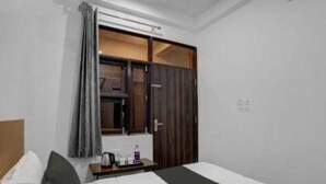 A hotel room with a bed, a nightstand, a window with curtains, and a wardrobe. - Hotel funday (Jaipur)