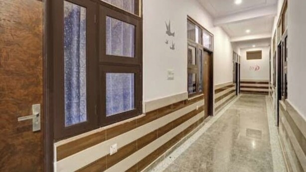 A hotel hallway with wooden paneling, a marble floor, and a door with frosted glass panels. - Hotel funday (Jaipur)