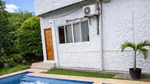 A two-story house with a swimming pool, a wooden door, and a potted plant.