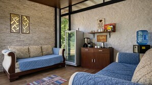 A modern room with a stone wall, a sofa, a cabinet, and a refrigerator.