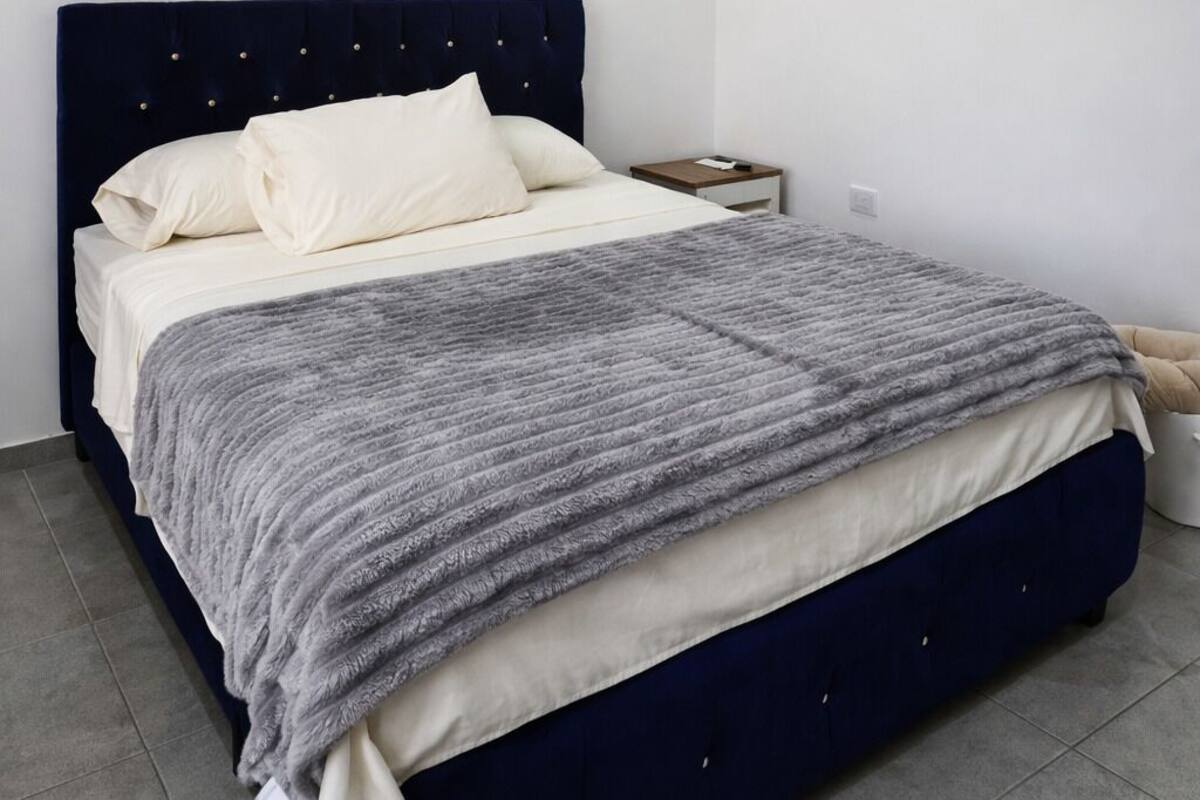 A bedroom with a bed, nightstand, and a single light fixture.