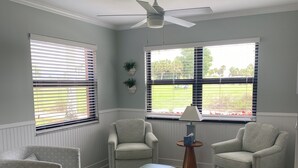 Ein Wohnzimmer mit zwei Sesseln, einem Couchtisch und einem Deckenventilator.