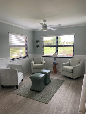 A living room with two armchairs, a coffee table, and a ceiling fan. - Cozy 2-bedroom condo in Tropic Schooner, Hammock Bay, Naples FL (Naples)
