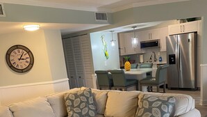 Ein modernes Wohnzimmer mit Ecksofa, Essbereich und einer Küche mit Edelstahlgeräten.