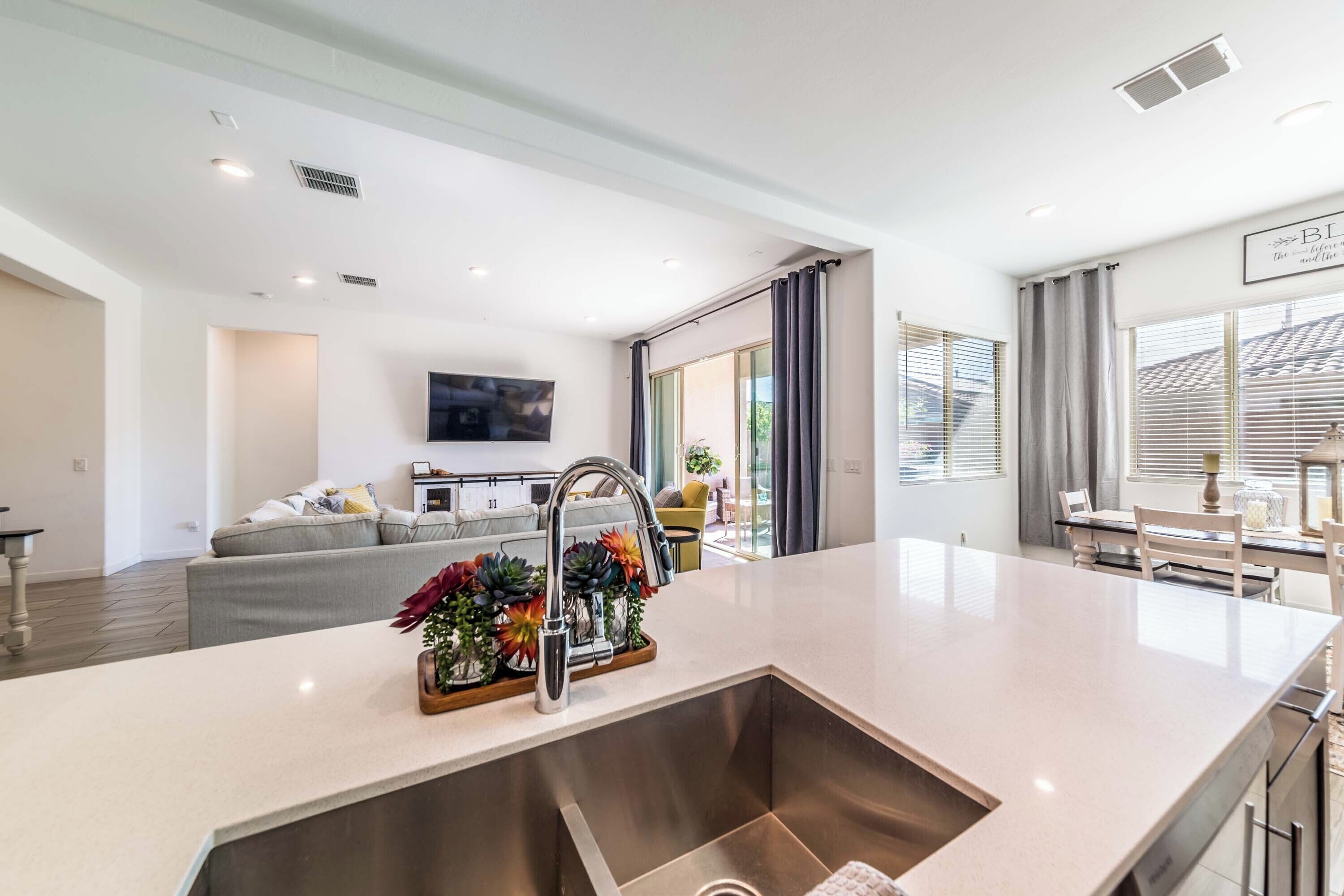 A modern kitchen with a central island, a built-in sink, and a dining area with a table and chairs.
