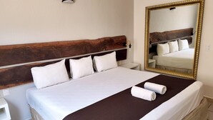 A neatly made bed with white linens and a brown accent, a large mirror with a gold frame, and a wooden headboard. - Days Inn By Wyndham Playa Del Carmen (Playa del Carmen)