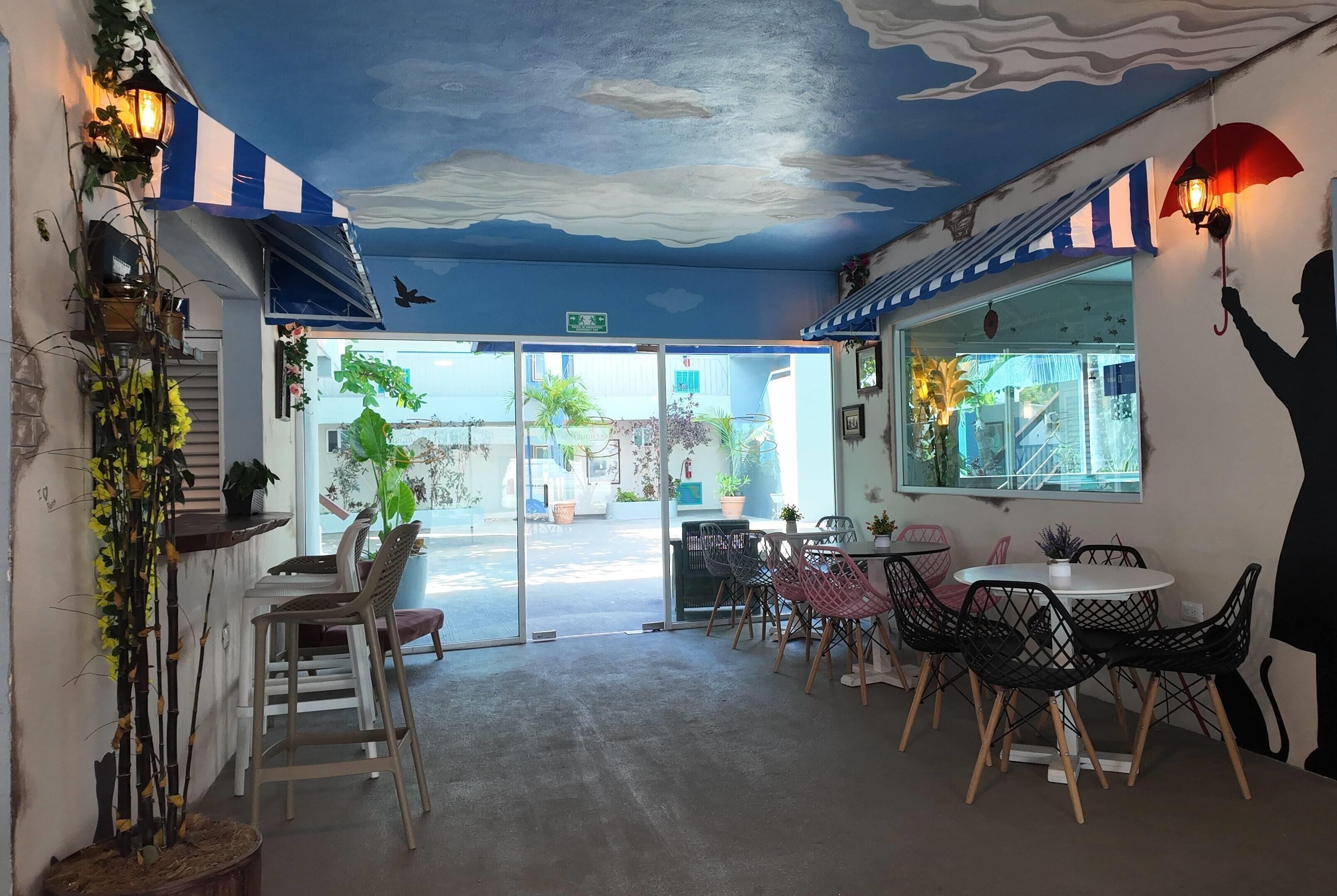 A restaurant interior with a blue and white striped awning, a ceiling mural, and a view of the street outside.