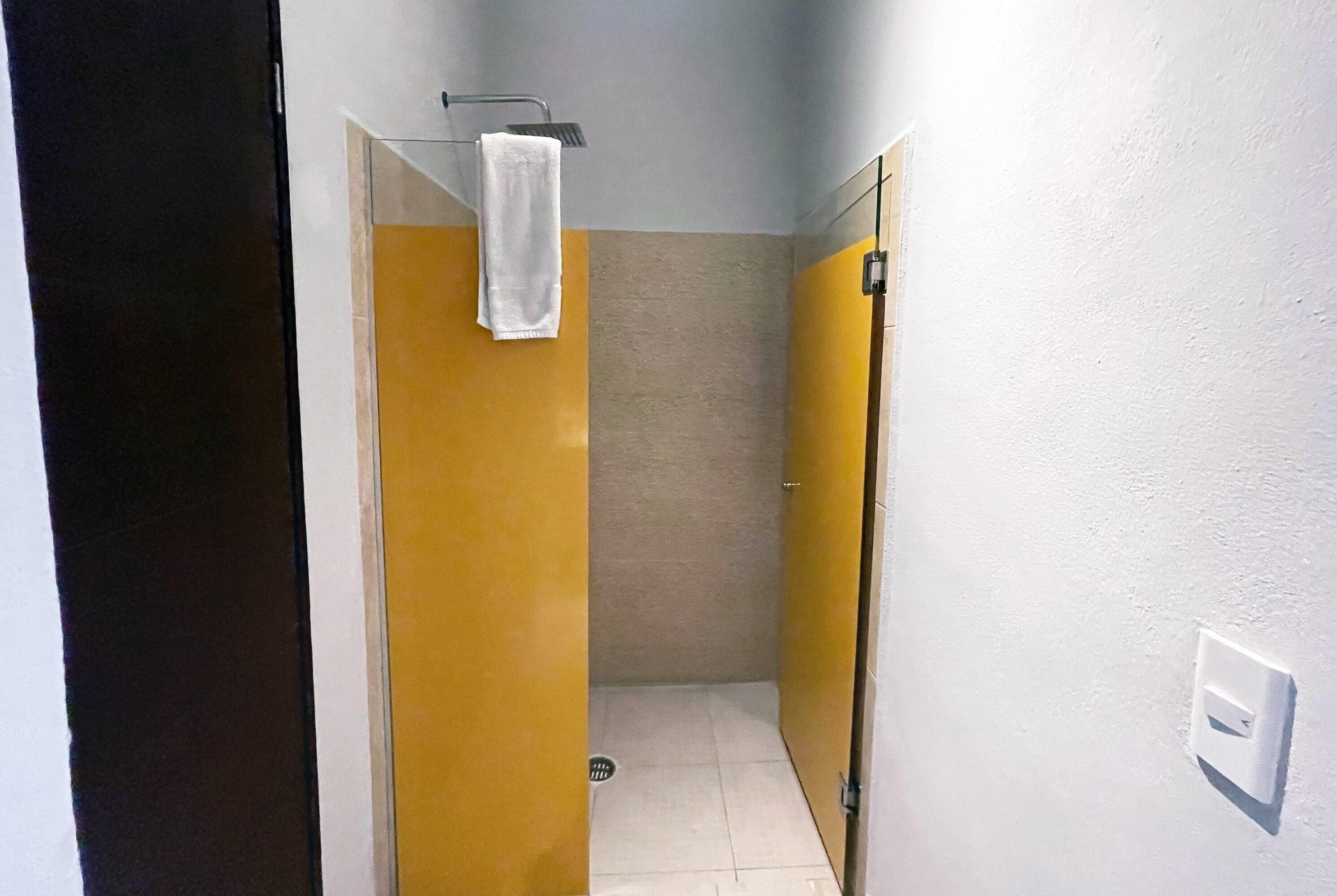 A narrow hallway with yellow and white walls, a white towel hanging on a rack, and a light switch on the wall.