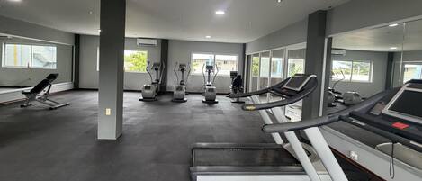 Un gimnasio con cintas de correr, elípticas y una máquina de remo.