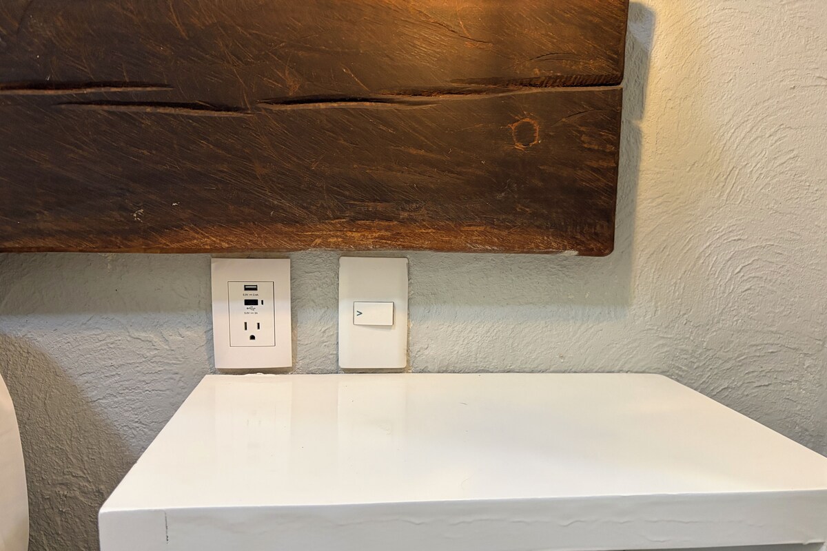 A white countertop with two electrical outlets and a switch on a textured wall.