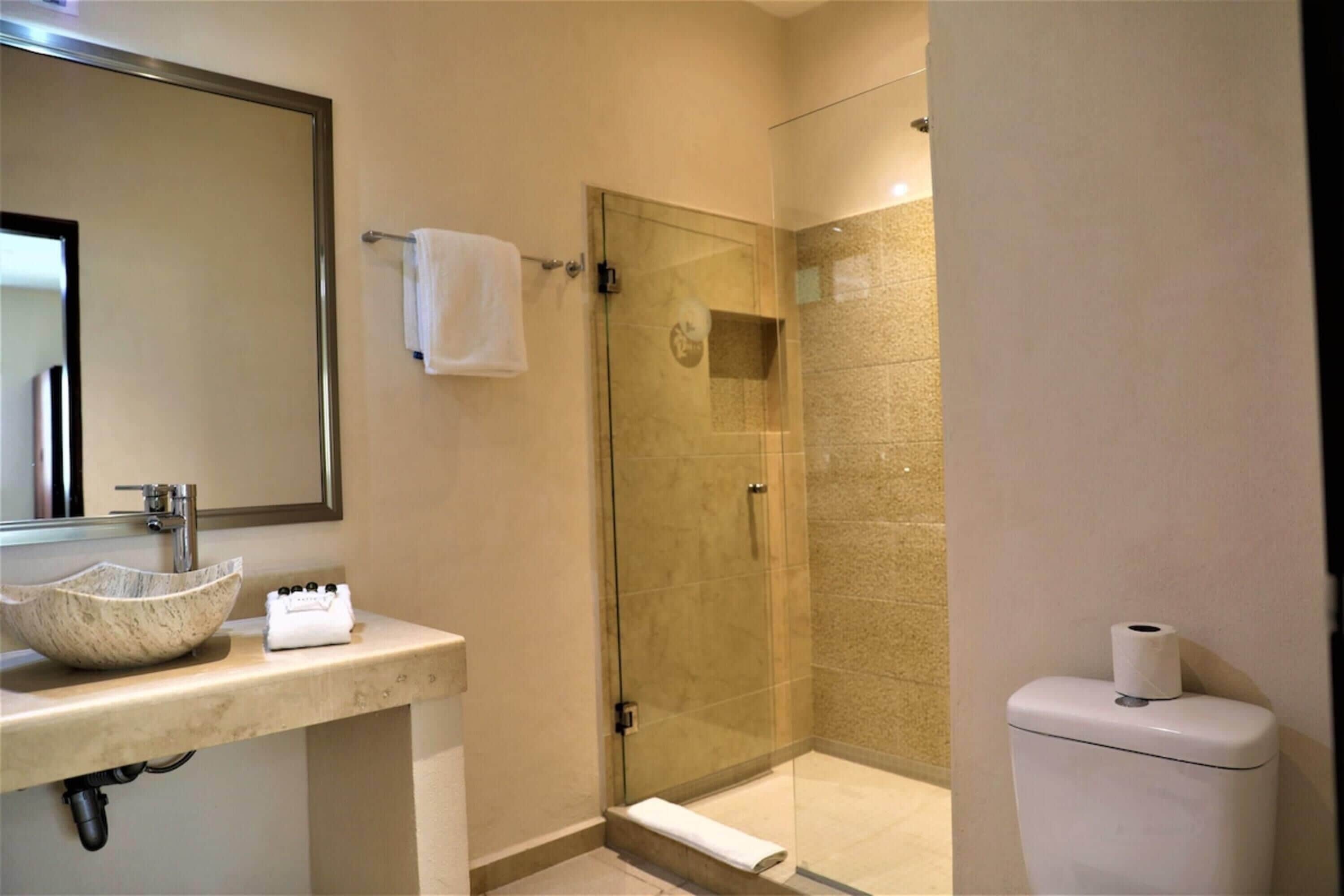 Un baño con ducha de vidrio, un lavabo con lavamanos de mármol y un inodoro.