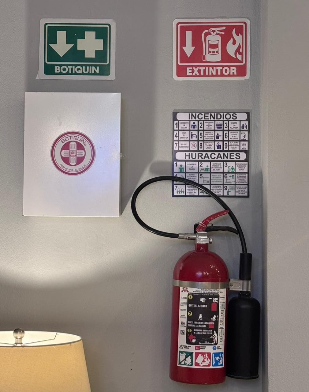 Un mur avec des panneaux d’indication pour les situations d’urgence, un extincteur et une trousse de premiers secours.