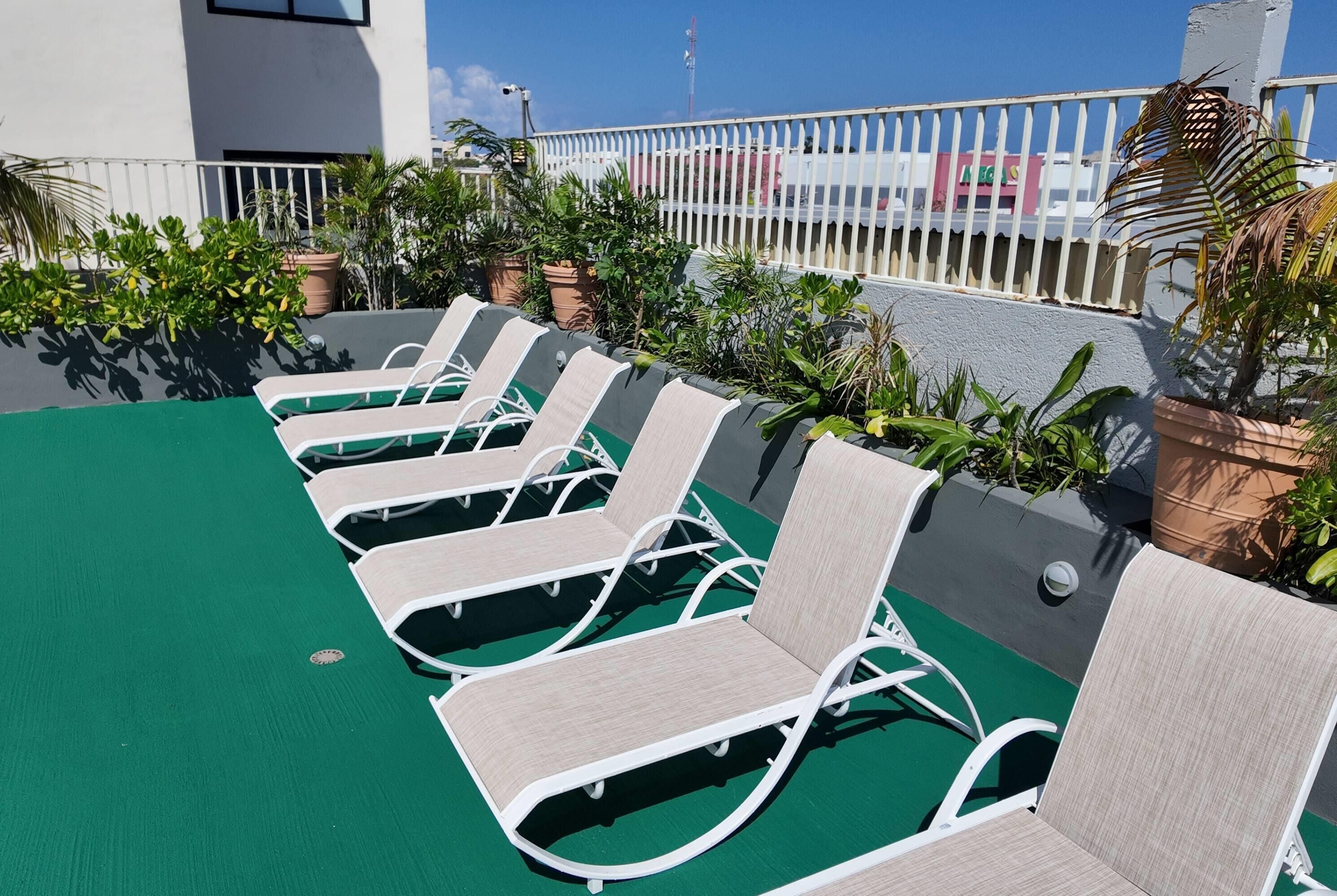 A rooftop deck with lounge chairs and potted plants.