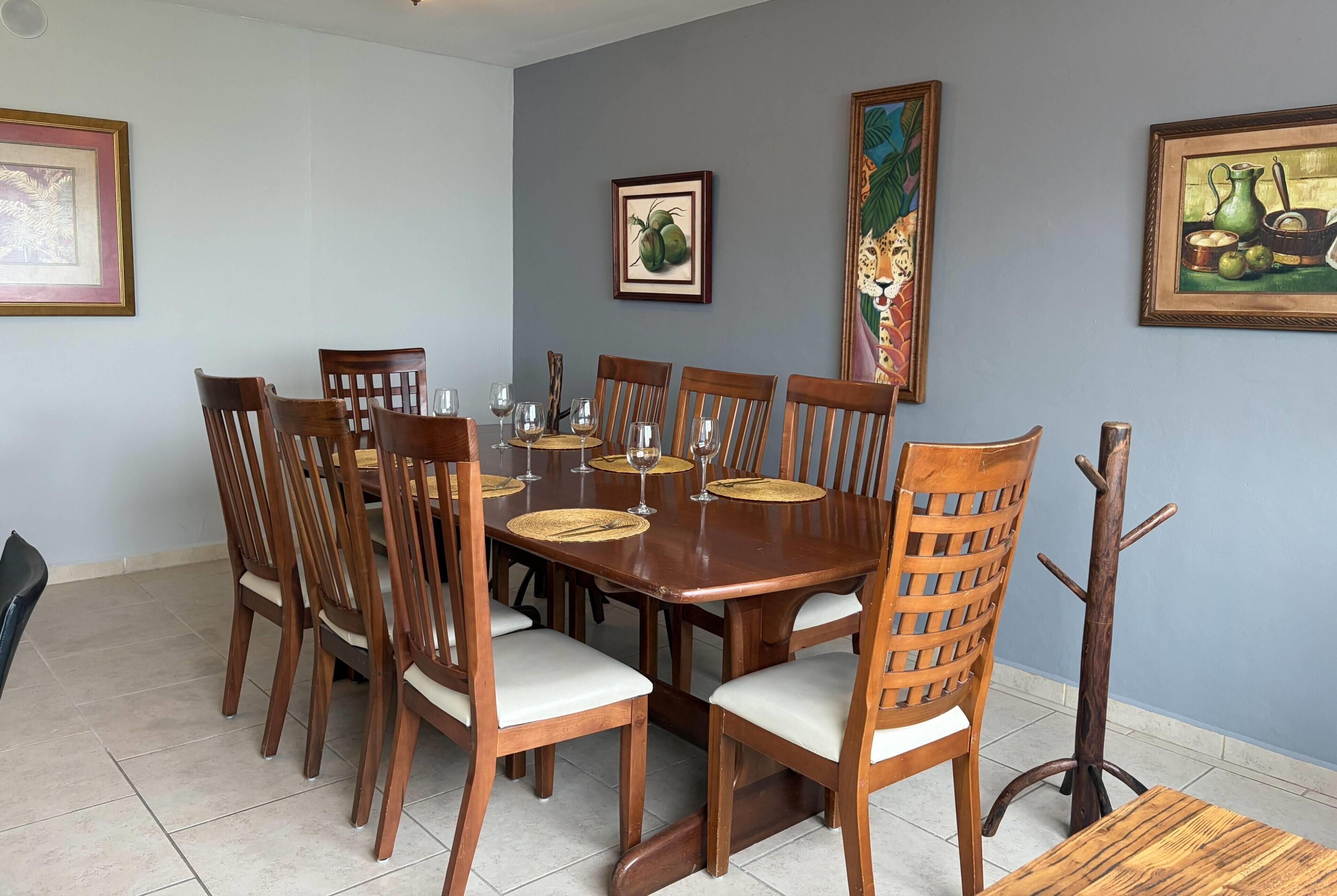 Uma sala de jantar com mesa de madeira, cadeiras e um cabideiro.
