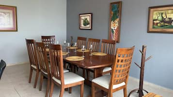 Uma sala de jantar com mesa de madeira, cadeiras e um cabideiro.