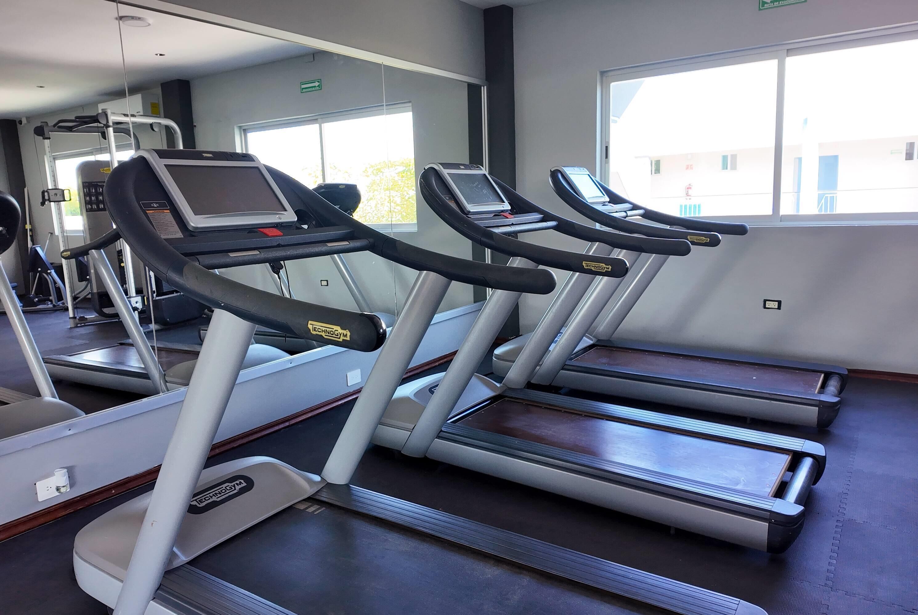 A gym with treadmills, mirrors, and exercise equipment.