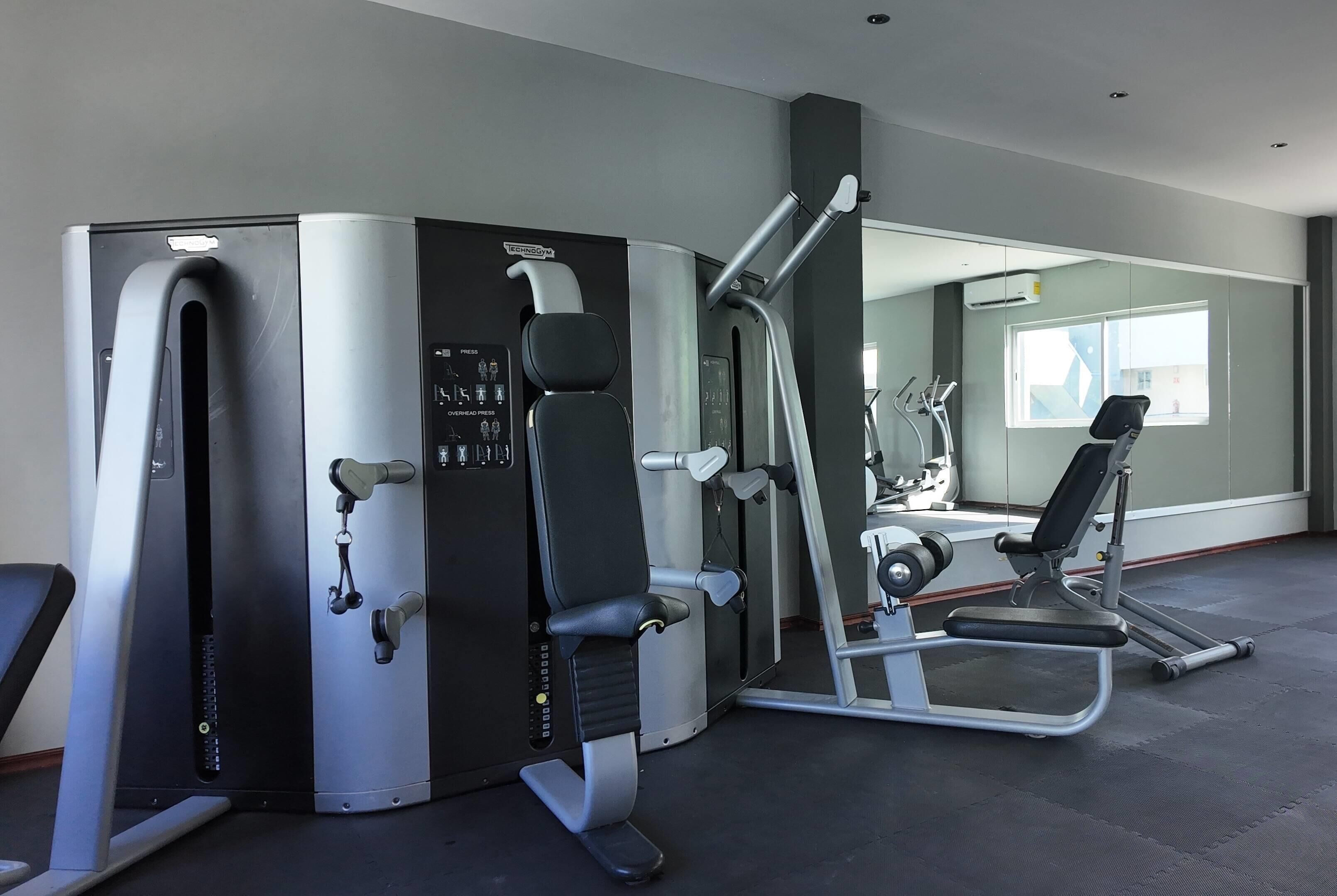 A gym with exercise equipment, a wall-mounted air conditioning unit, and a window with a view.
