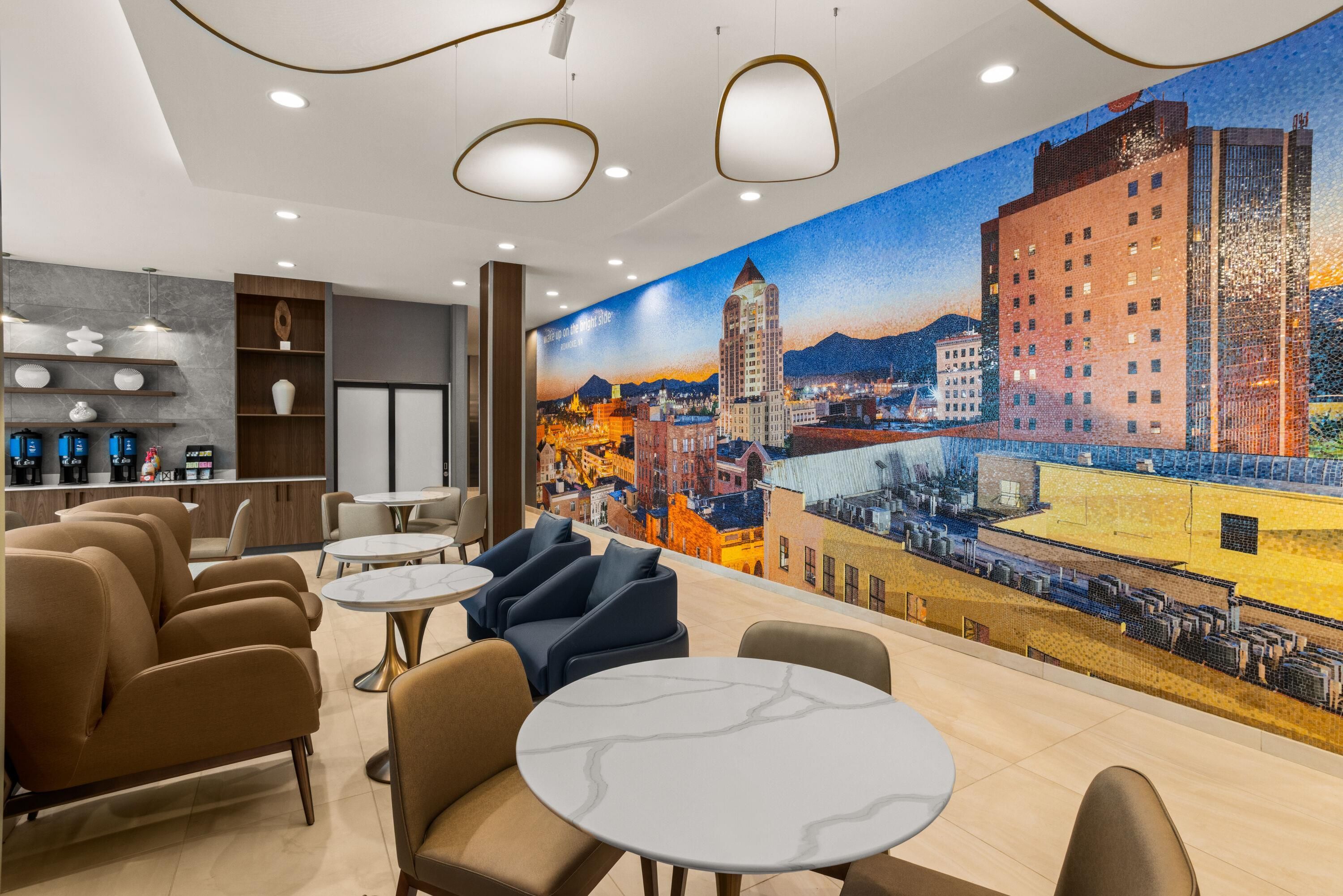A modern lounge area with seating, a coffee bar, and a cityscape mural on the wall.