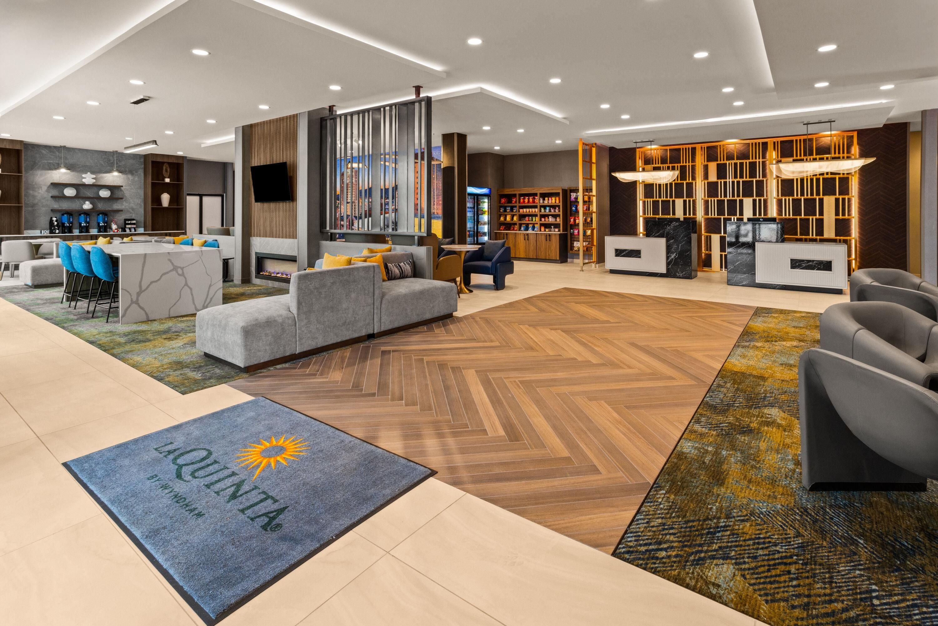 Un hall d’hôtel moderne avec un comptoir d’accueil, un espace salon et une cheminée.