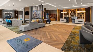 Un hall d’hôtel moderne avec un comptoir d’accueil, un espace salon et une cheminée.