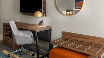 A modern room with a desk, chair, and a small orange ottoman.