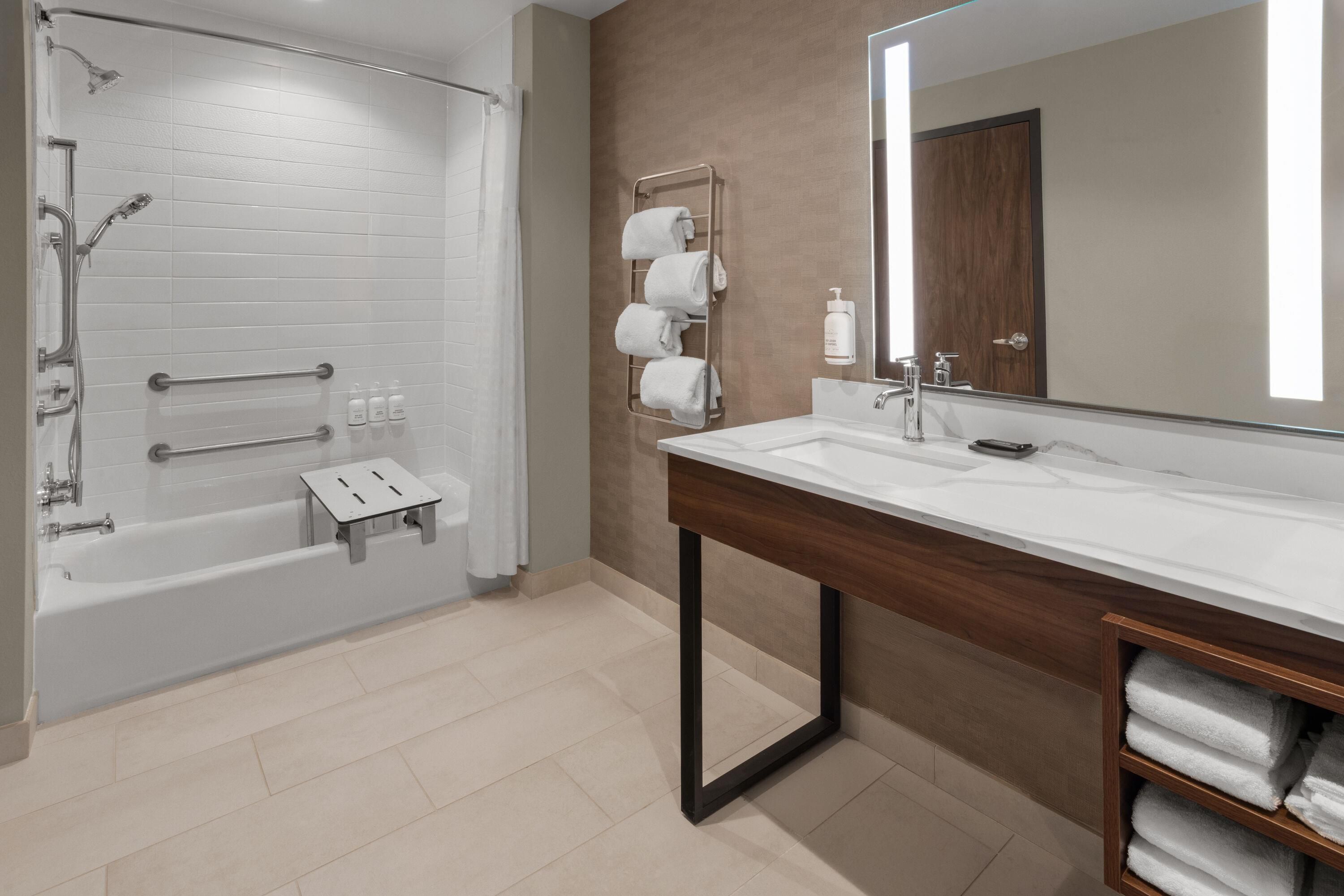 A modern bathroom with a walk-in shower, a vanity with a mirror, and a towel rack.