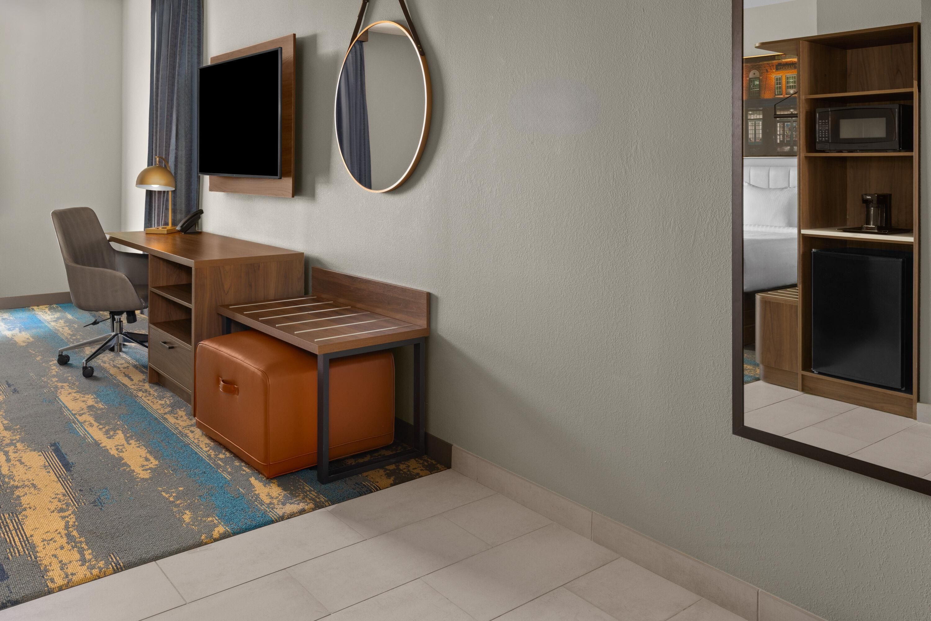 A hotel room with a desk, chair, and a large mirror.