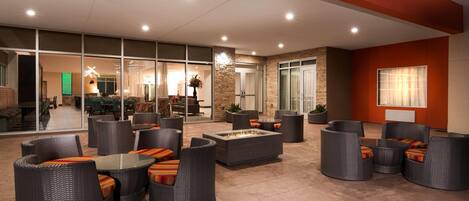 A spacious outdoor seating area with wicker furniture and a central fire feature.