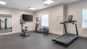 Un gimnasio con cintas de correr, elípticas y una bicicleta estática.