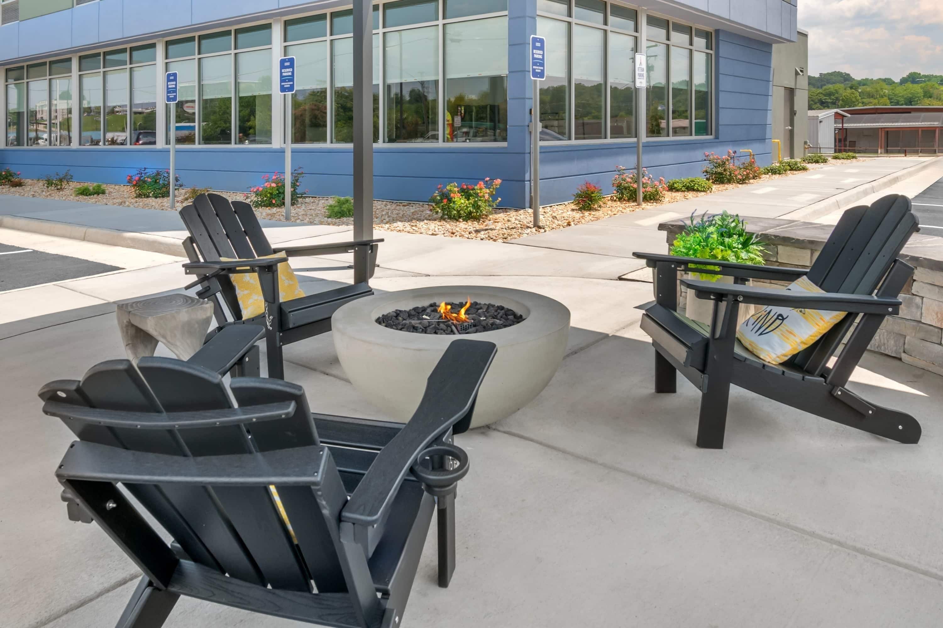 An outdoor seating area with Adirondack chairs and a fire pit.
