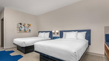 Una habitación de hotel con dos camas, un cabecero azul, una pared blanca y una alfombra azul.