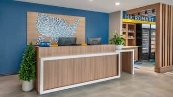 A reception desk with two computer monitors, a plant, and a wall art of a blue dot map.